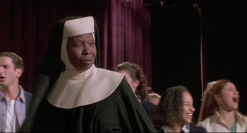 Movie still from “Sister Act 2: Back in the Habit” (1993), directed by Bill Duke – An older woman wearing a nun's outfit in front of a group of people; Close Up shot, Over the shoulder angle
