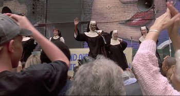 Movie still from “Sister Act 2: Back in the Habit” (1993), directed by Bill Duke – A group of people dressed up as nuns singing; Medium shot, Low angle