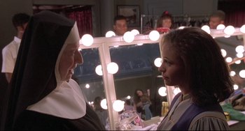 Movie still from “Sister Act 2: Back in the Habit” (1993), directed by Bill Duke – A nun is talking to a woman in front of a mirror; Medium shot, Over the shoulder angle