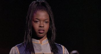 Movie still from “Sister Act 2: Back in the Habit” (1993), directed by Bill Duke – A woman with long braids wearing a blue and yellow outfit; Close Up shot, Over the shoulder angle