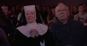 Movie still from “Sister Act 2: Back in the Habit” (1993), directed by Bill Duke – A nun and an old man are posing for a picture; Medium shot, Low angle