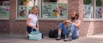 Movie still from “Sisters” (2015), directed by Jason Moore – Two people sitting on the ground with a bag; Wide shot, High angle