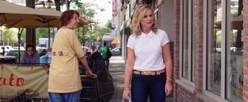 Movie still from “Sisters” (2015), directed by Jason Moore – A woman in white shirt and jeans walking down a street; Medium shot, Over the shoulder angle