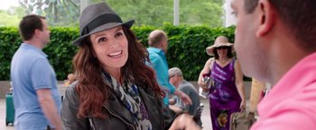 Movie still from “Sisters” (2015), directed by Jason Moore – A woman in a hat and a scarf smiling for the camera; Medium shot, Over the shoulder angle