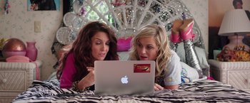 Movie still from “Sisters” (2015), directed by Jason Moore – Two women looking at a laptop computer on a bed; Medium shot, High angle