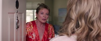 Movie still from “Sisters” (2015), directed by Jason Moore – An older woman wearing a red robe looking at a younger woman; Close Up shot, Over the shoulder angle