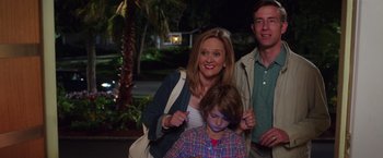 Movie still from “Sisters” (2015), directed by Jason Moore – A woman and two men standing next to a child; Medium shot, Over the shoulder angle