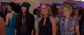 Movie still from “Sisters” (2015), directed by Jason Moore – A group of people standing in a room with lights in the background; Medium shot, Over the shoulder angle