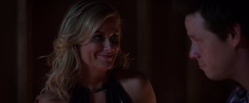 Movie still from “Sisters” (2015), directed by Jason Moore – A woman smiling for the camera in a dark room; Close Up shot, Over the shoulder angle