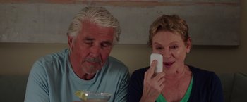 Movie still from “Sisters” (2015), directed by Jason Moore – An older man and a woman looking at a cell phone; Close Up shot, High angle
