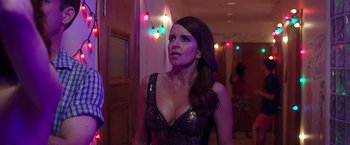 Movie still from “Sisters” (2015), directed by Jason Moore – A woman in a black and silver dress in front of lights; Medium shot, Over the shoulder angle