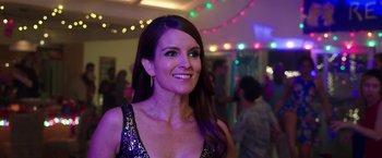 Movie still from “Sisters” (2015), directed by Jason Moore – A woman in a black dress smiling for the camera; Close Up shot, Over the shoulder angle