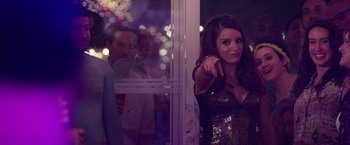 Movie still from “Sisters” (2015), directed by Jason Moore – A woman in a gold dress pointing to the camera; Medium shot, Over the shoulder angle