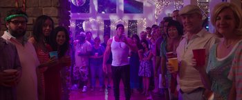 Movie still from “Sisters” (2015), directed by Jason Moore – A group of people standing around a room; Wide shot, Over the shoulder angle