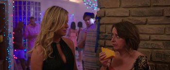 Movie still from “Sisters” (2015), directed by Jason Moore – Two women are talking to each other at a party; Medium shot, Over the shoulder angle