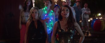 Movie still from “Sisters” (2015), directed by Jason Moore – A group of people standing in front of a crowd; Medium shot, Over the shoulder angle