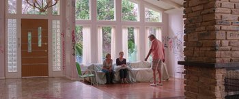 Movie still from “Sisters” (2015), directed by Jason Moore – Three people sitting on a couch in front of a large window; Wide shot, High angle