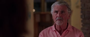 Movie still from “Sisters” (2015), directed by Jason Moore – An older man in a pink shirt looks at the camera; Close Up shot, Over the shoulder angle
