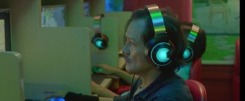 A man with headphones is sitting at a computer desk