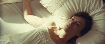 Movie still from “Sleep Tight” (2011), directed by Jaume Balagueró – A beautiful young woman laying on a bed; Close Up shot, Overhead angle