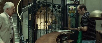 Movie still from “Sleep Tight” (2011), directed by Jaume Balagueró – A wooden table sitting in front of an iron gate; Wide shot, Low angle