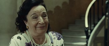 Movie still from “Sleep Tight” (2011), directed by Jaume Balagueró – An older woman wearing pearls and a floral shirt; Close Up shot, Over the shoulder angle