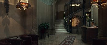 Movie still from “Sleep Tight” (2011), directed by Jaume Balagueró – A hallway with stairs and a rug and a plant; Wide shot, High angle