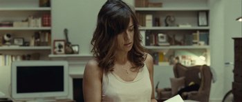 Movie still from “Sleep Tight” (2011), directed by Jaume Balagueró – A woman in a white tank top is looking down; Close Up shot, Over the shoulder angle