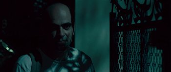 Movie still from “Sleep Tight” (2011), directed by Jaume Balagueró – A man with a bald head is standing in a dark room; Close Up shot, Low angle