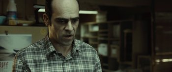 Movie still from “Sleep Tight” (2011), directed by Jaume Balagueró – A man in a plaid shirt is looking at the camera; Close Up shot, Over the shoulder angle
