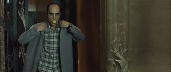 Movie still from “Sleep Tight” (2011), directed by Jaume Balagueró – A man holding a piece of food in his hand; Medium shot, Over the shoulder angle