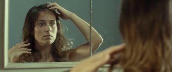 Movie still from “Sleep Tight” (2011), directed by Jaume Balagueró – A woman looking in the mirror while brushing her hair; Close Up shot, Over the shoulder angle