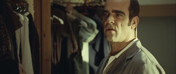Movie still from “Sleep Tight” (2011), directed by Jaume Balagueró – A man in a suit standing in front of a closet; Close Up shot, Over the shoulder angle