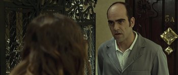 Movie still from “Sleep Tight” (2011), directed by Jaume Balagueró – A man in a gray suit looking at a woman in a white shirt; Close Up shot, Over the shoulder angle