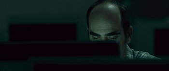 Movie still from “Sleep Tight” (2011), directed by Jaume Balagueró – A man looking at a computer screen at night; Close Up shot, Over the shoulder angle