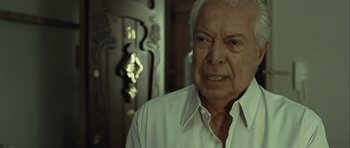 Movie still from “Sleep Tight” (2011), directed by Jaume Balagueró – An older man in a white dress shirt; Close Up shot, Over the shoulder angle