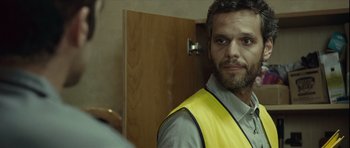 Movie still from “Sleep Tight” (2011), directed by Jaume Balagueró – A man wearing a yellow vest standing in front of a mirror; Close Up shot, Over the shoulder angle