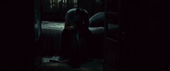 Movie still from “Sleep Tight” (2011), directed by Jaume Balagueró – A man sitting on top of a bed in a dark room; Wide shot, High angle