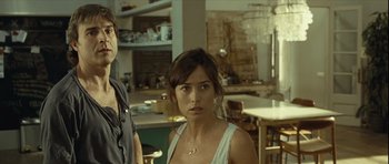 Movie still from “Sleep Tight” (2011), directed by Jaume Balagueró – A woman standing next to another woman in a room; Medium shot, Over the shoulder angle