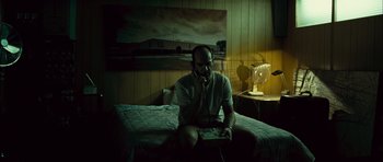 Movie still from “Sleep Tight” (2011), directed by Jaume Balagueró – A man sitting on top of a bed talking on the phone; Wide shot, Low angle