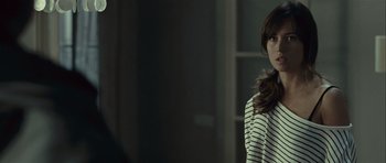 Movie still from “Sleep Tight” (2011), directed by Jaume Balagueró – A woman in a striped shirt standing in front of a window; Close Up shot, Over the shoulder angle
