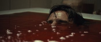 Movie still from “Sleep Tight” (2011), directed by Jaume Balagueró – A man laying in a pool of red liquid; Close Up shot, High angle