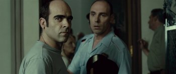 Movie still from “Sleep Tight” (2011), directed by Jaume Balagueró – Two men standing next to each other in front of a wall; Close Up shot, Over the shoulder angle