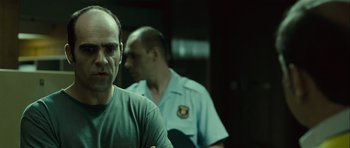 Movie still from “Sleep Tight” (2011), directed by Jaume Balagueró – A man in a gray shirt and a man in a blue shirt; Close Up shot, Over the shoulder angle