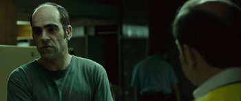 Movie still from “Sleep Tight” (2011), directed by Jaume Balagueró – A man standing in front of a mirror in a room; Close Up shot, Over the shoulder angle