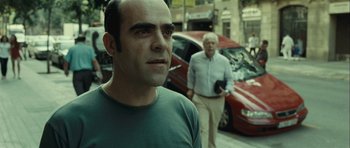 Movie still from “Sleep Tight” (2011), directed by Jaume Balagueró – A man standing next to another man on the street; Close Up shot, Over the shoulder angle