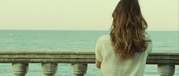 Movie still from “Sleep Tight” (2011), directed by Jaume Balagueró – A woman looking out over the ocean from a balcony; Medium shot, Over the shoulder angle