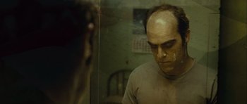 Movie still from “Sleep Tight” (2011), directed by Jaume Balagueró – A man with a bald head looking in a mirror; Close Up shot, Over the shoulder angle