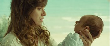Movie still from “Sleep Tight” (2011), directed by Jaume Balagueró – A woman holding a baby in her arms and looking at the camera; Close Up shot, Over the shoulder angle