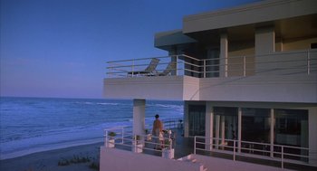 Movie still from “Sleeping with the Enemy” (1991), directed by Joseph Ruben – A man standing on the balcony of a beach house; Extreme Wide shot, High angle